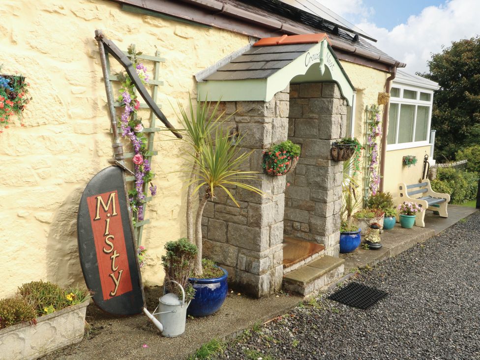 An entrance with a stone porch and flower pots at Crow's Nest Cottage Tynygongl near Benllech