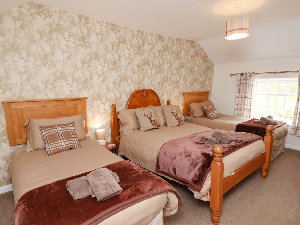 A bedroom with three beds and a window at Boundcliffe Farm Allerston near Pickering
