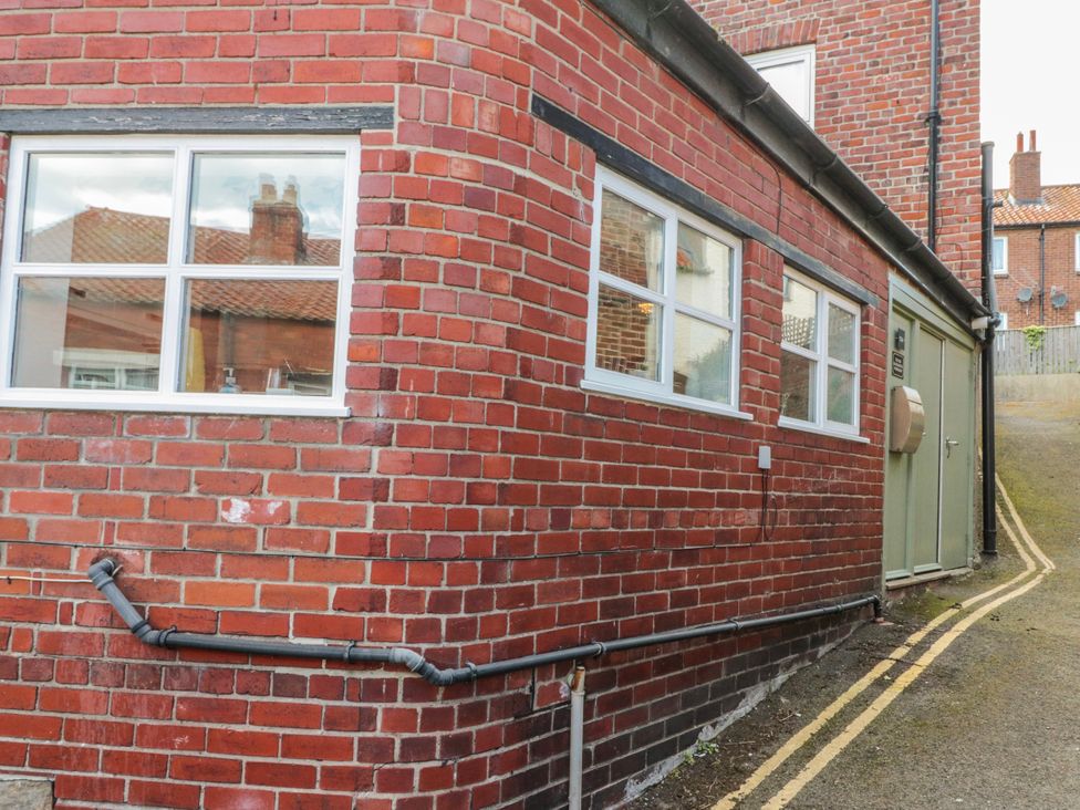 An exterior view of a brick wall with windows and a door at The Old Blacksmith's Workshop in Whitby