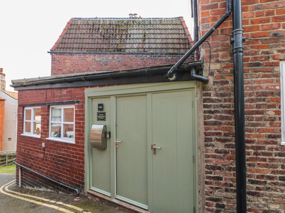 An outdoor view of a green door and brick wall at The Old Blacksmith's Workshop in Whitby