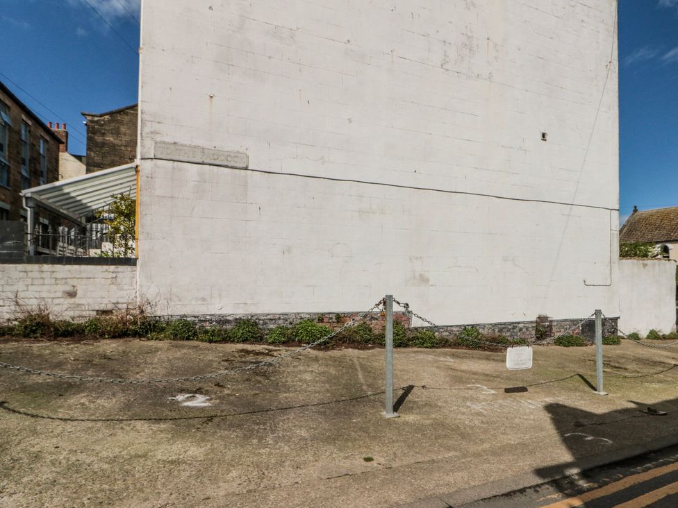 An outdoor area with a building wall and chain link fencing at The Old Blacksmith's Workshop in Whitby