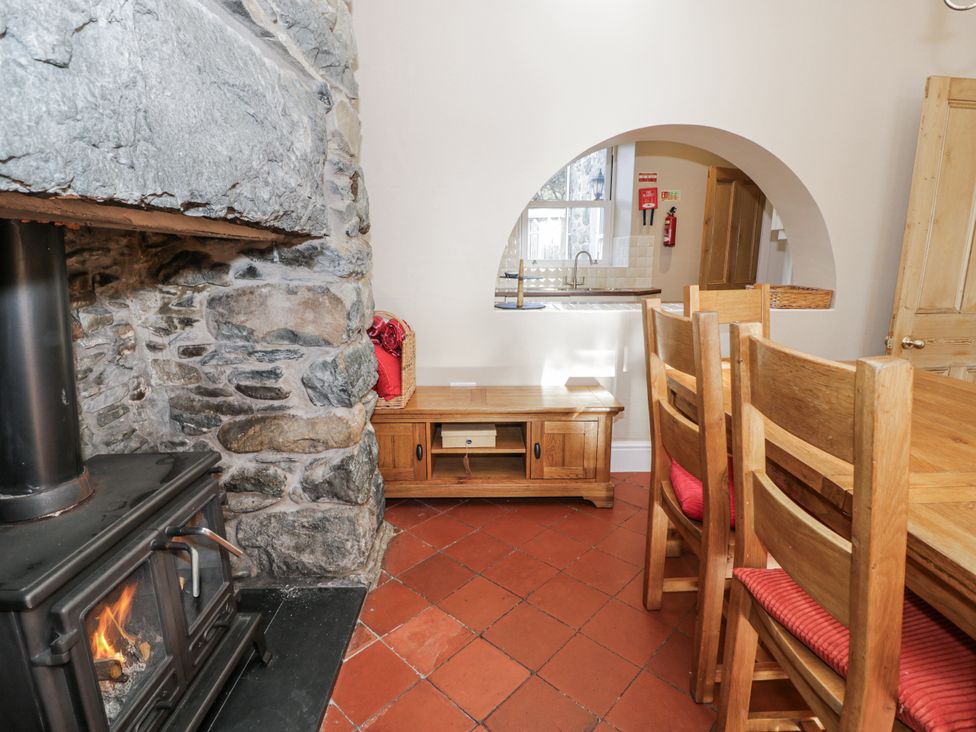 A dining area with a fireplace and wooden furniture at Tyddyn Goronwy in Talybont