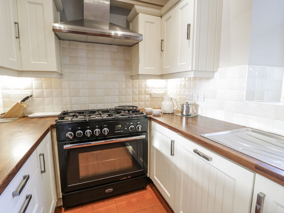 A kitchen with a black stove and white cabinets at Tyddyn Goronwy in Talybont