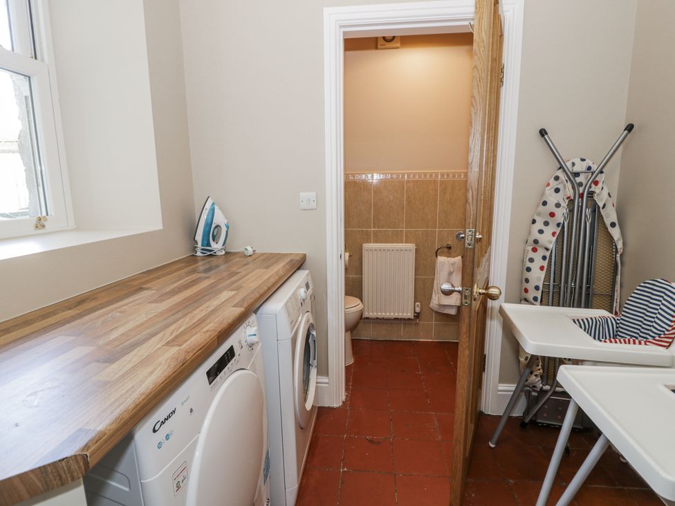 A laundry room with a washing machine and ironing board at Tyddyn Goronwy in Talybont