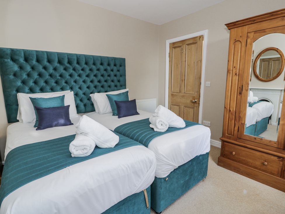 A bedroom with two beds and a mirror at Tyddyn Goronwy in Talybont