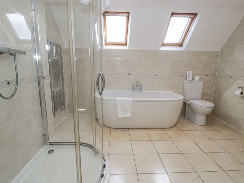 A bathroom with a shower, bathtub, toilet, and sink at Tyddyn Goronwy in Talybont