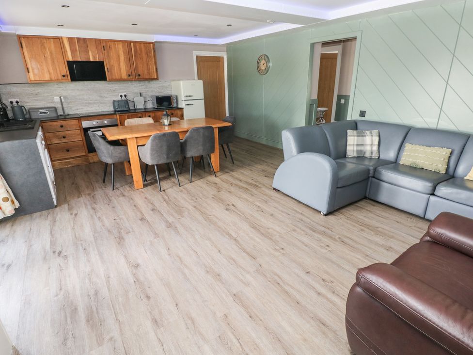 A living room with a kitchen area and dining table at Meadow View in Laugharne