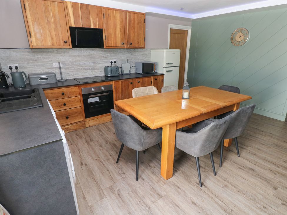 A kitchen with a wooden table and chairs at Meadow View in Laugharne