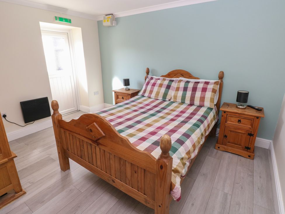 A bedroom with a wooden bed and nightstand at Meadow View in Laugharne