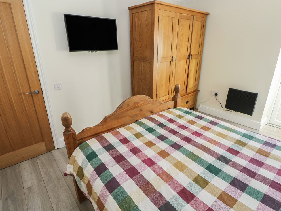 A bedroom with a bed, wardrobe, and television at Meadow View in Laugharne