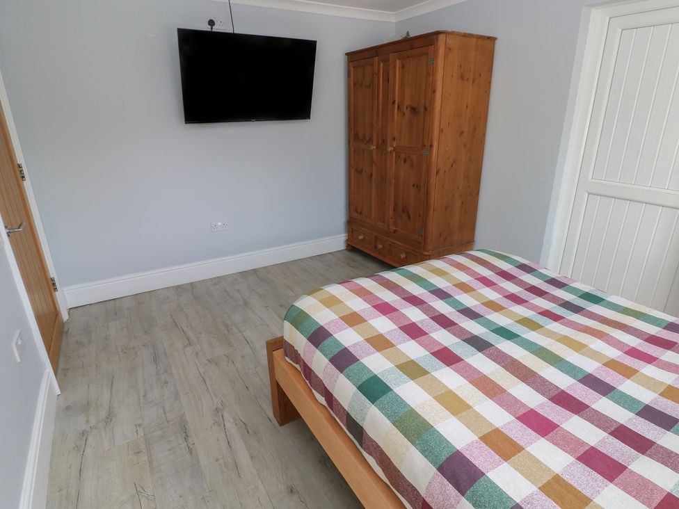 A bedroom with a bed and a wardrobe at Meadow View in Laugharne