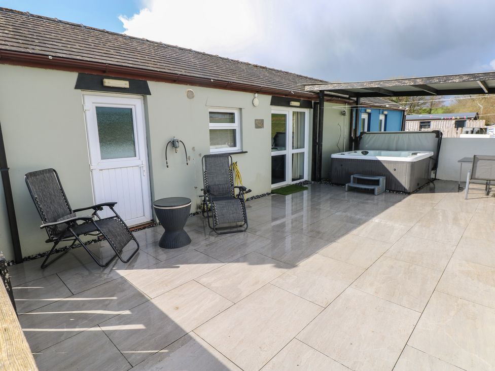 An outdoor area with a hot tub and chairs at Meadow View Laugharne