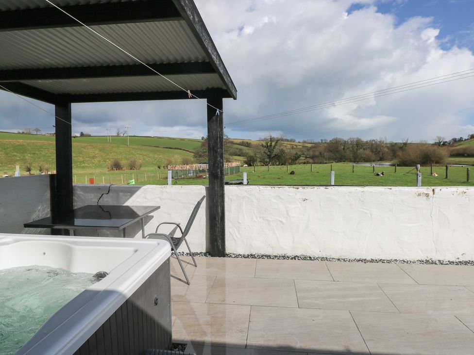 An outdoor area with a hot tub and seating at Meadow View in Laugharne