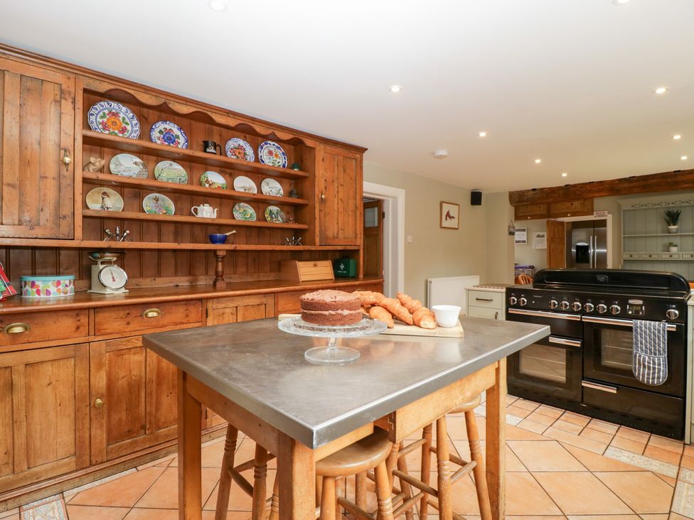A kitchen with a table, oven, and shelves at The Croft in Vowchurch near Peterchurch