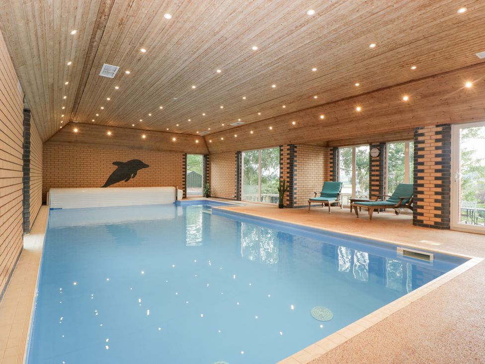 An indoor pool area with chairs and large windows at The Croft in Vowchurch near Peterchurch
