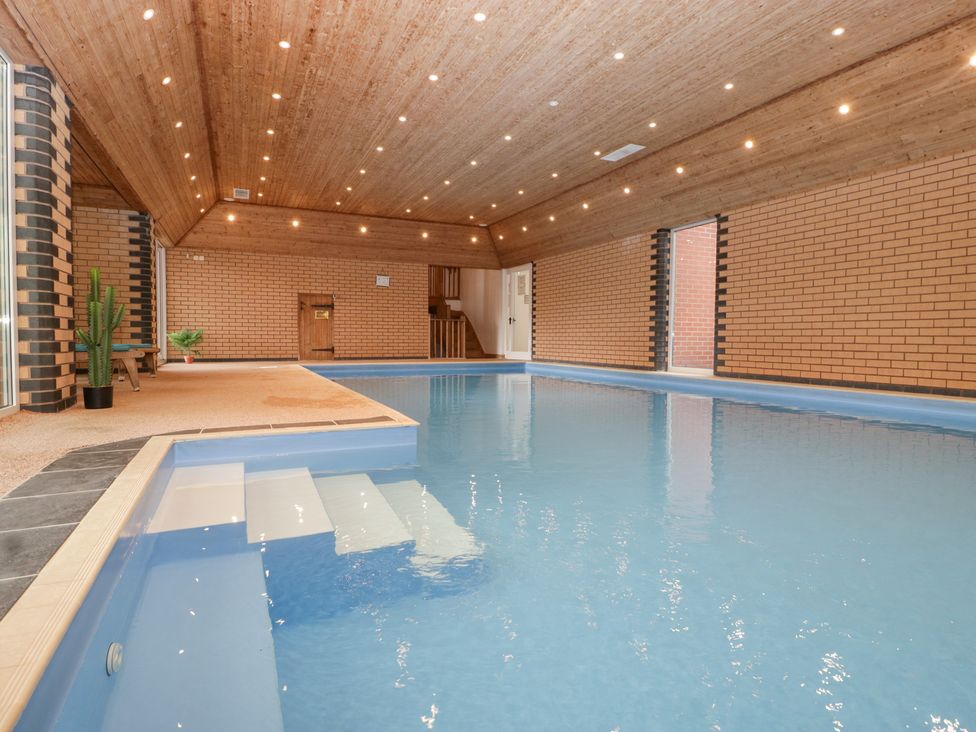 An indoor pool with steps and potted plants at The Croft in Vowchurch near Peterchurch