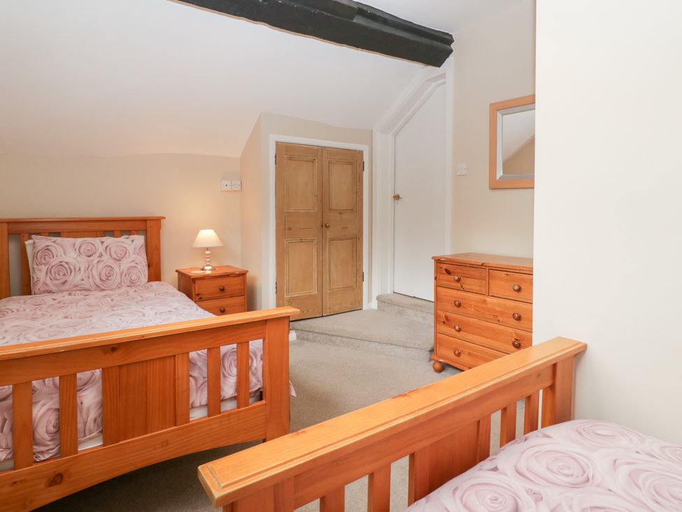 A bedroom with two beds and a wardrobe at The Croft in Vowchurch near Peterchurch