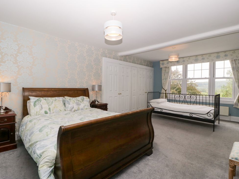 A bedroom with a bed, side table, wardrobe, and window at The Croft in Vowchurch near Peterchurch