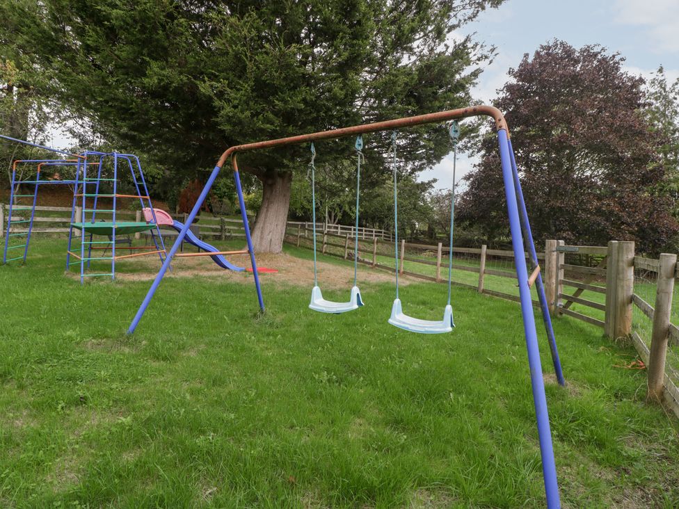 A swingset and play structure in an outdoor area at The Croft in Vowchurch near Peterchurch
