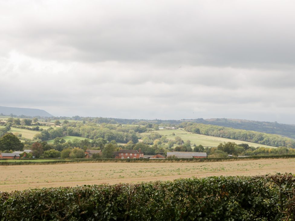 A view of fields and trees with houses in the distance at The Croft in Vowchurch near Peterchurch