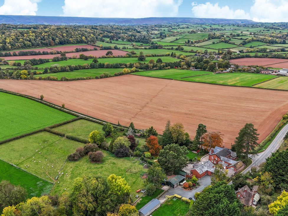 An aerial view of fields and a house with trees at The Croft in Vowchurch near Peterchurch