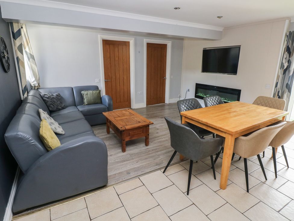 A living room with a sofa, coffee table, dining table and chairs at Dylan's Court in Laugharne