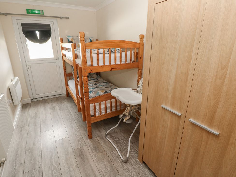 A bedroom with a bunk bed and a high chair at Dylan's Court in Laugharne