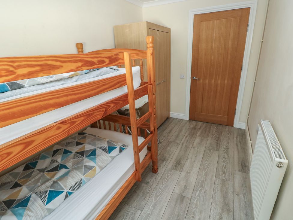 A bedroom with a bunk bed and wardrobe at Dylan's Court in Laugharne