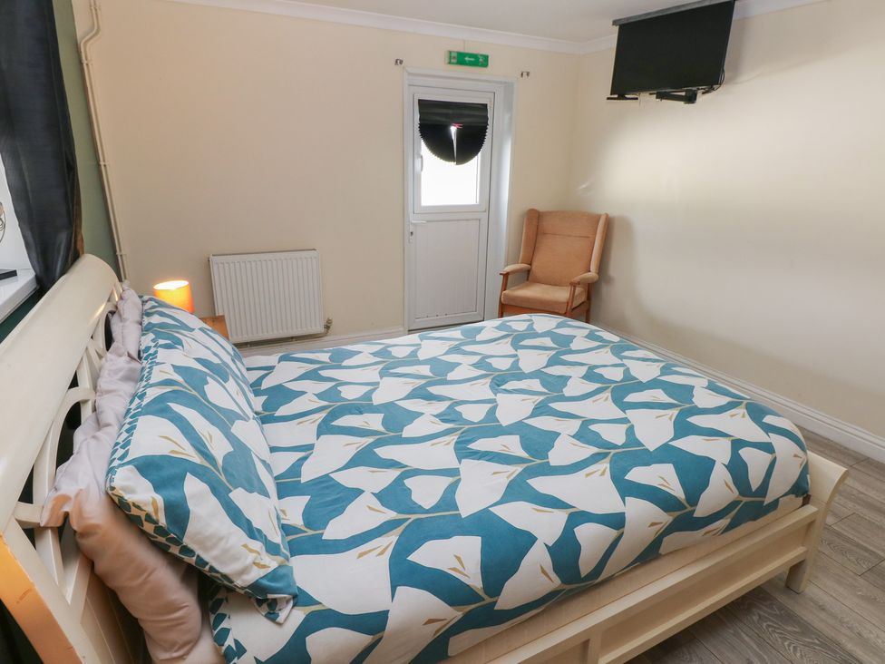 A bedroom with a bed, chair and television at Dylan's Court in Laugharne