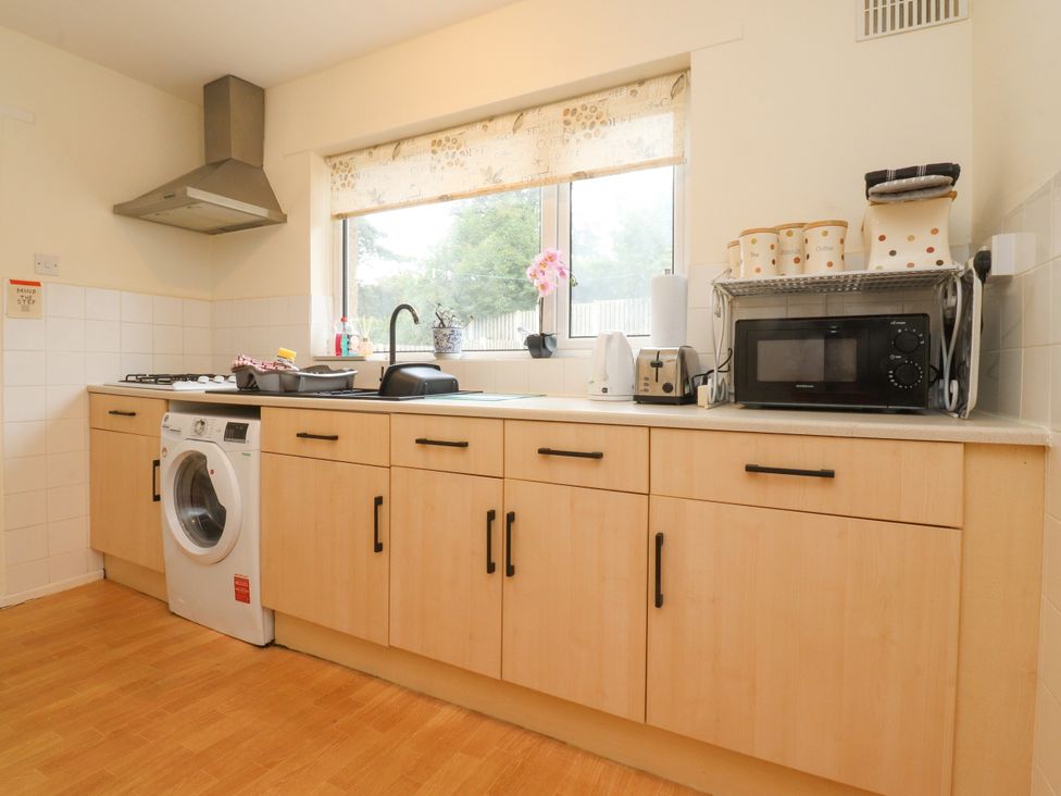 A kitchen with a sink, stove, washing machine and microwave at Wynnville in Embsay near Skipton