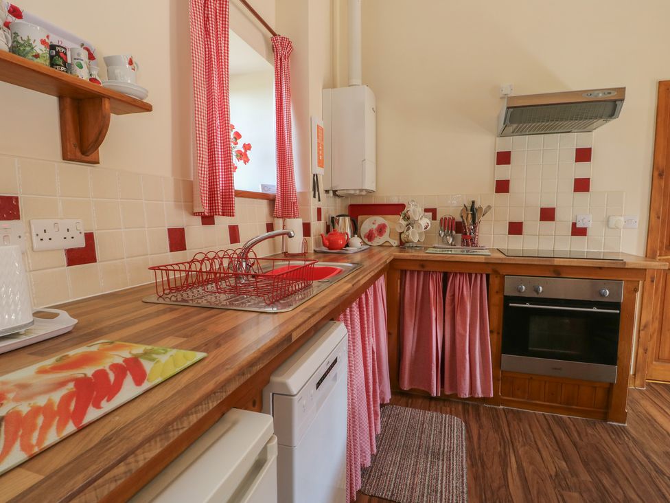 A kitchen with sink and oven at Poppy Cottage in Caeathro near Caernarfon