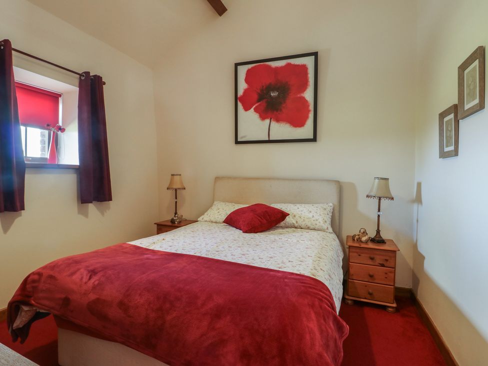 A bedroom with a bed and bedside table at Poppy Cottage in Caeathro near Caernarfon