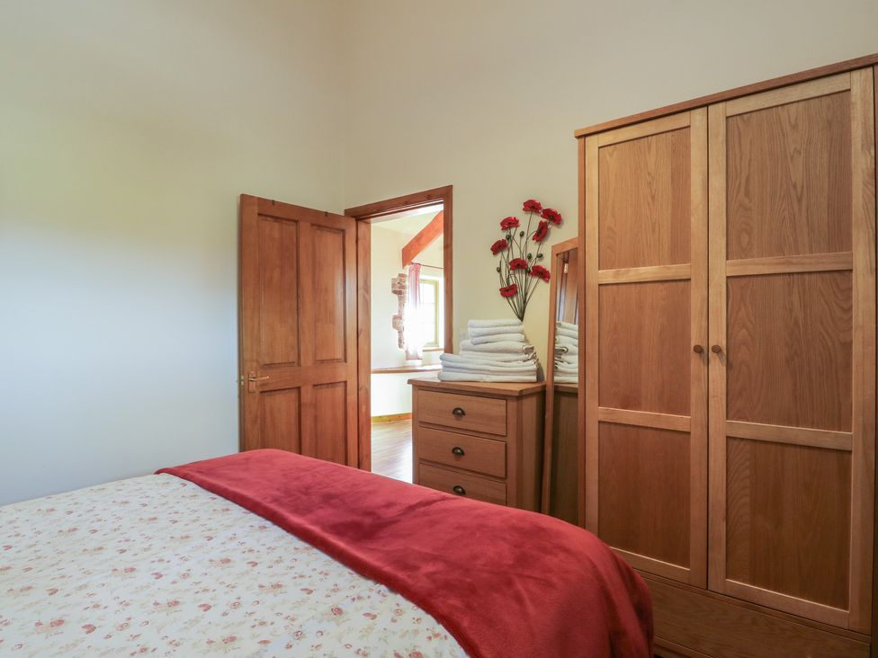 A bedroom with a bed and wooden furniture at Poppy Cottage in Caeathro near Caernarfon