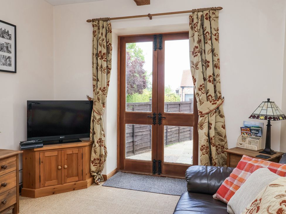 A living room with a television and door at Croft Granary in Stillington near Easingwold and York