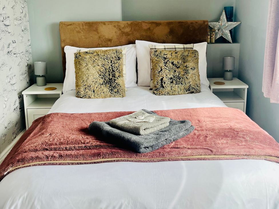 A bed with pillows and blankets at Corvette in Trearddur Bay