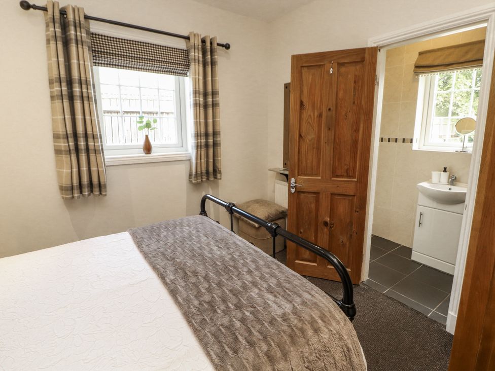 A bedroom with a bed and a door leading to a bathroom at White Gables in Great Clifton near Cockermouth