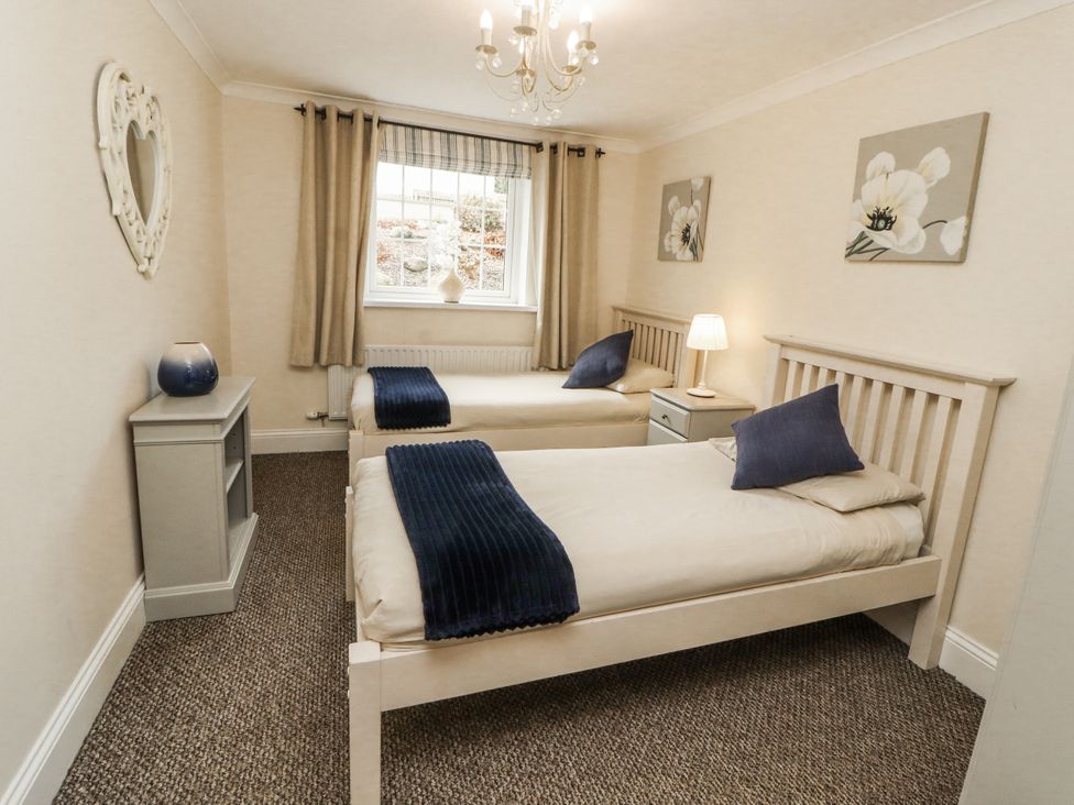 A bedroom with two beds and a window at White Gables in Great Clifton near Cockermouth