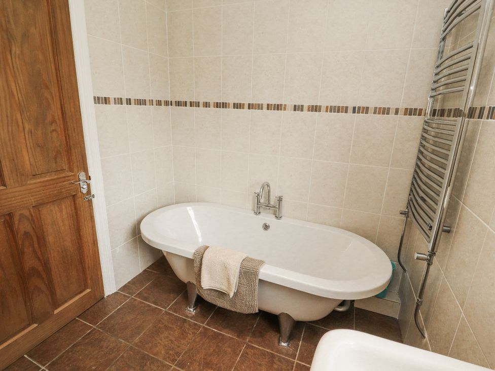 A bathroom with a bathtub and towel rack at White Gables in Great Clifton near Cockermouth