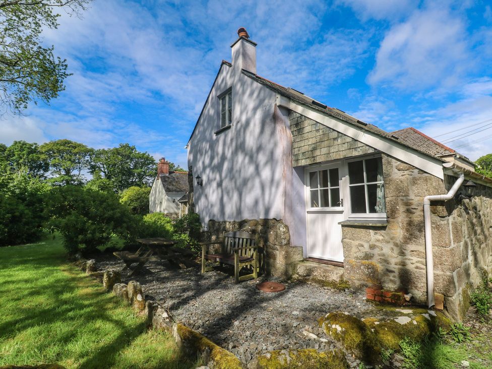A house with a bench and table surrounded by grass at Longhouse in St Keverne, Lizard Peninsula