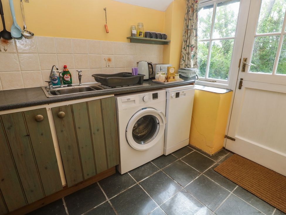 A kitchen with a sink, cabinets, and a washing machine at Longhouse, St Keverne, Lizard Peninsula