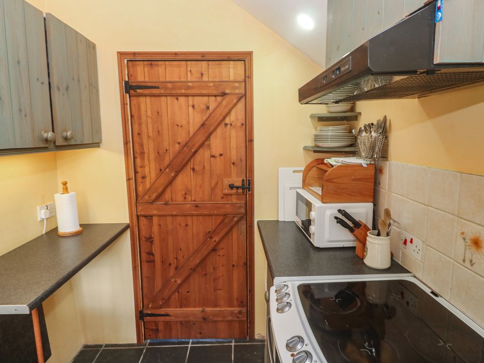 A kitchen with wooden door and appliances at Longhouse St Keverne, Lizard Peninsula