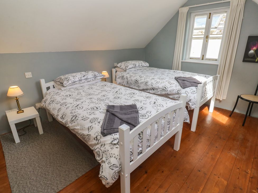 A bedroom with two beds and a window at Longhouse in St Keverne, Lizard Peninsula
