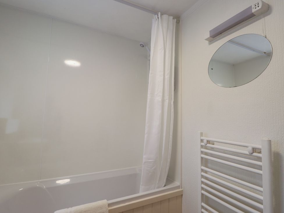 A bathroom with a bathtub and a shower curtain at Lag-Uaine in Staffin