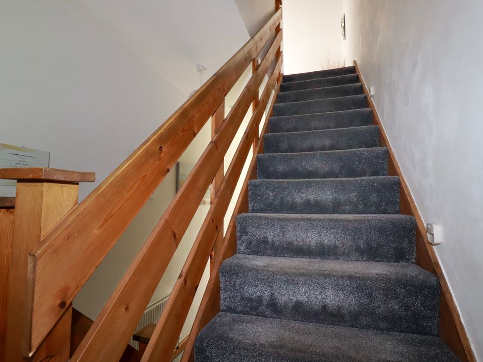 A staircase with dark carpet and wooden railing at Sunnyvale in Bugle near St Austell