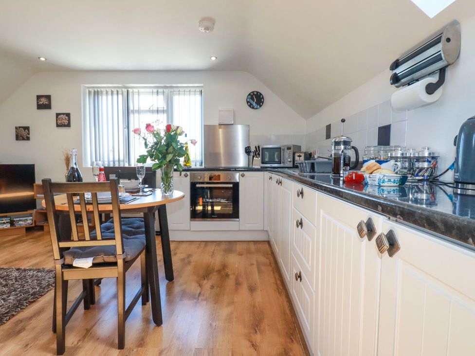 A kitchen with white cabinets a round table with chairs and flowers on the table at Sunnyvale in Bugle near St Austell