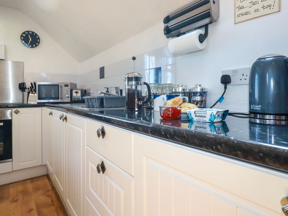 A kitchen countertop with a kettle a microwave a french press jars and scones with jam and cream at Sunnyvale in Bugle near St Austell