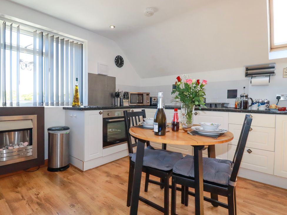 A kitchen with a wooden dining table set with plates cups and flowers at Sunnyvale in Bugle near St Austell