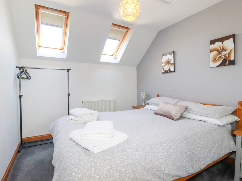 A bedroom with a double bed folded towels skylight windows and a clothes rack at Sunnyvale in Bugle near St Austell