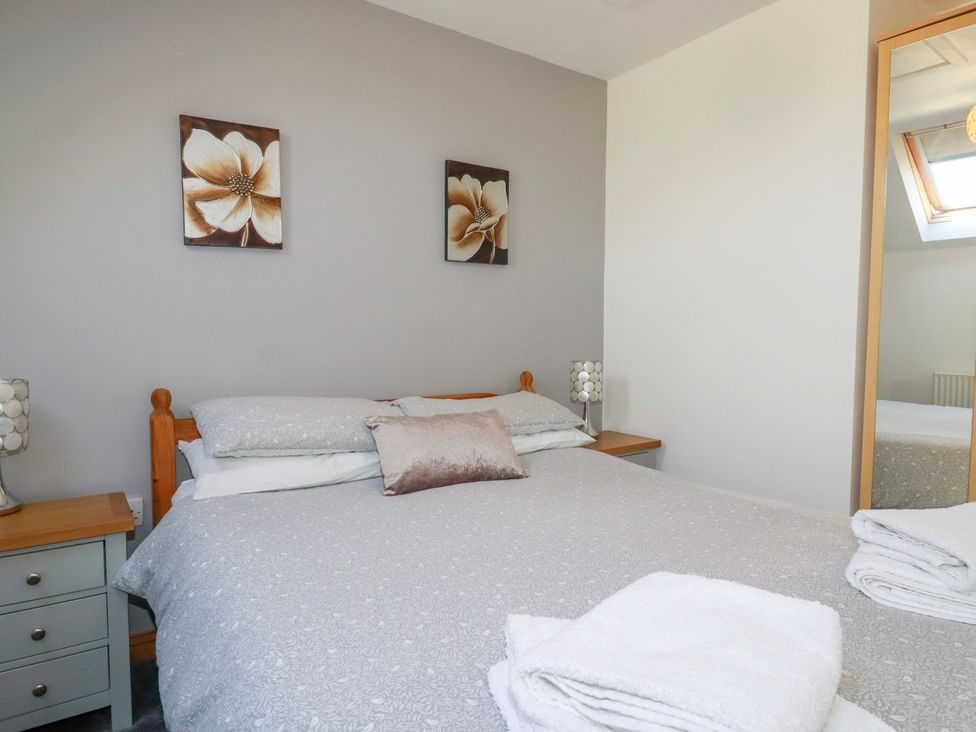 A bedroom with a bed side tables lamps and a mirror at Sunnyvale in Bugle near St Austell