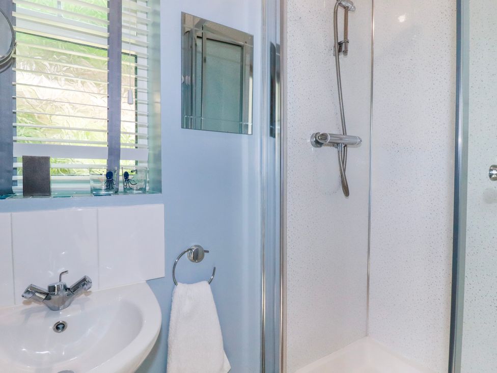 A bathroom with a sink a towel ring with a towel a window with blinds and a shower cubicle at Sunnyvale Bugle near St Austell